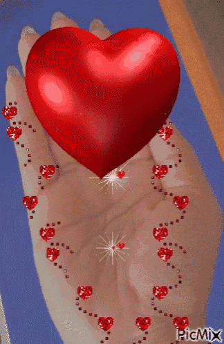 a woman 's hand is holding a red heart with hearts around it