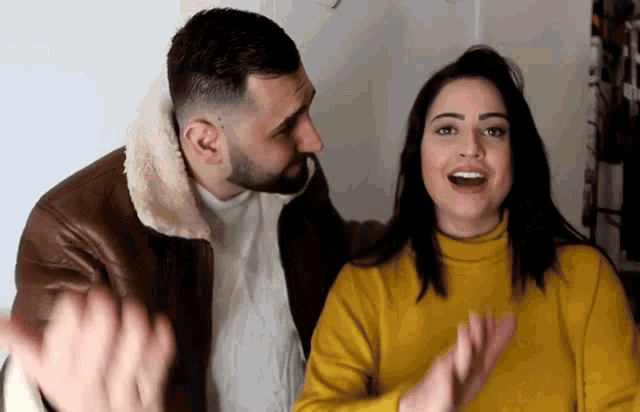 a man kisses a woman on the cheek while she looks surprised