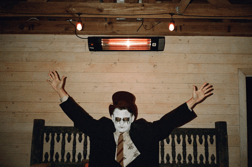 a man in a suit and top hat has his arms outstretched in front of a heater