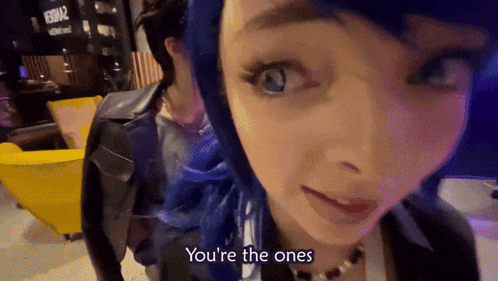 a woman with blue hair says " you 're the ones " while looking at the camera