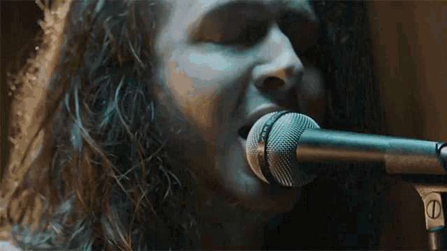 a close up of a person singing into a microphone with the letter s on it