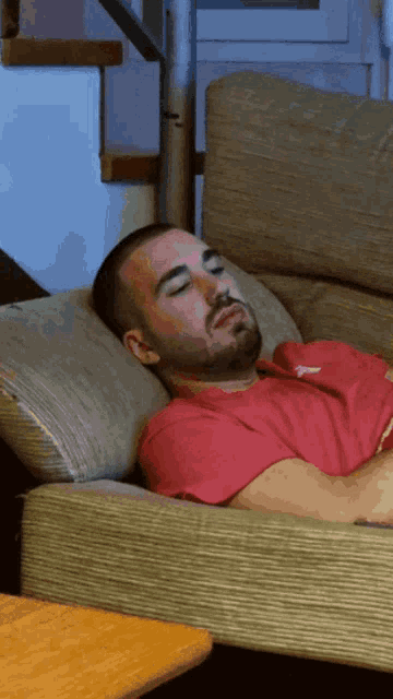 a man is sleeping on a couch and his shirt says reebok