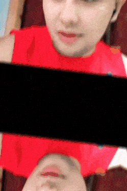 a woman in a red shirt is taking a picture of herself with a cell phone