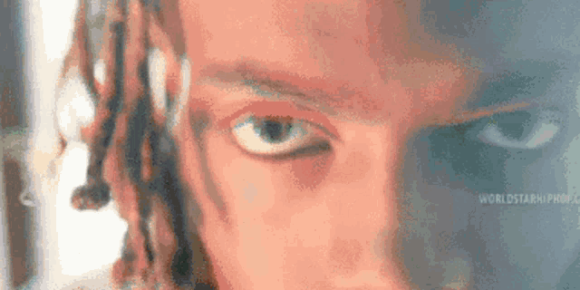 a close up of a person 's eyes with dreadlocks and a serious look on their face .
