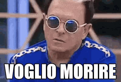 a man wearing sunglasses and a blue shirt with the words voglio morire written on it .