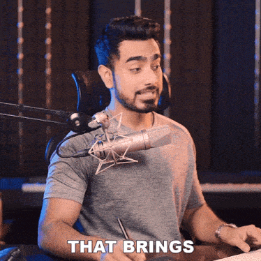 a man sitting in front of a microphone with the words that brings behind him