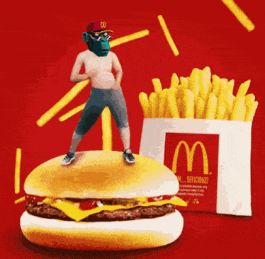 a man standing on top of a hamburger next to a mcdonald 's box of french fries