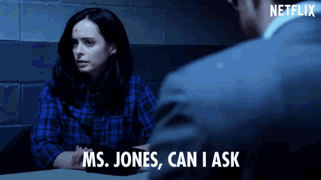 a woman in a blue plaid shirt is talking to a man in a suit and says ms. jones can i