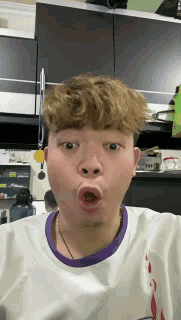 a man wearing a white shirt with a purple collar makes a funny face