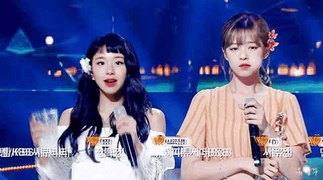 two girls are standing next to each other with microphones in their hands