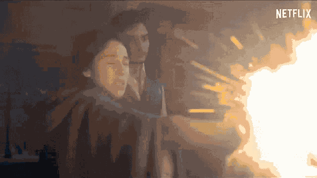a woman is holding a gun in front of a fire with a netflix logo in the background .
