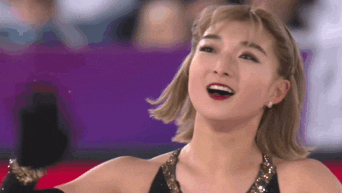 a close up of a woman wearing a black top and gold gloves smiling .