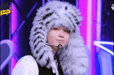 a person wearing a fur hat with a microphone on a stage