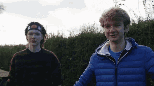 two young men standing next to each other one wearing a headband with a star on it and one wearing a blue jacket