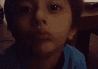 a close up of a young boy 's face making a funny face in a dark room .