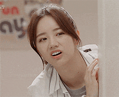 a close up of a woman making a funny face behind a wall