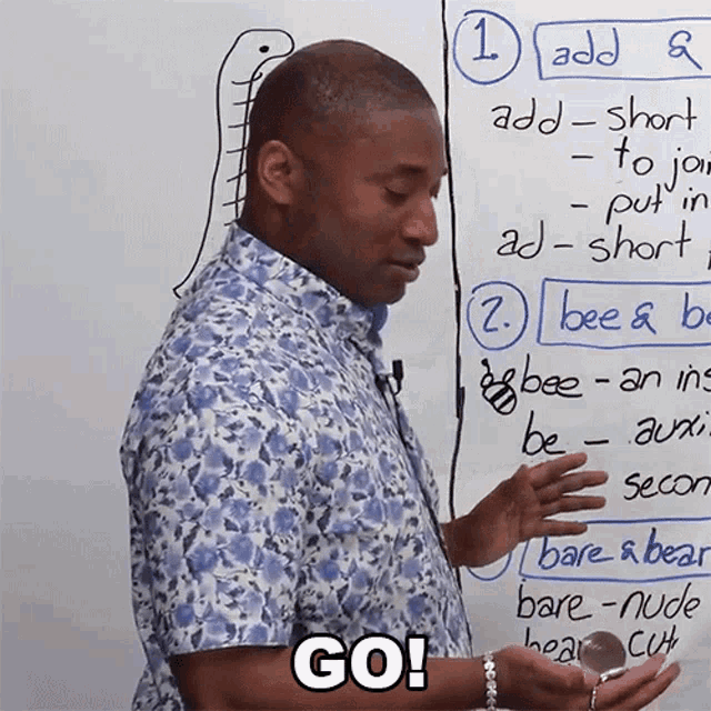 a man stands in front of a white board with the words go on the bottom
