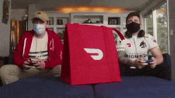 two men wearing masks are playing a video game with a red bag that says pioneer on it