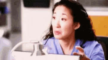 a woman in a blue scrub top is sitting in front of a computer monitor .