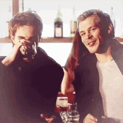 two men are sitting at a bar drinking alcohol