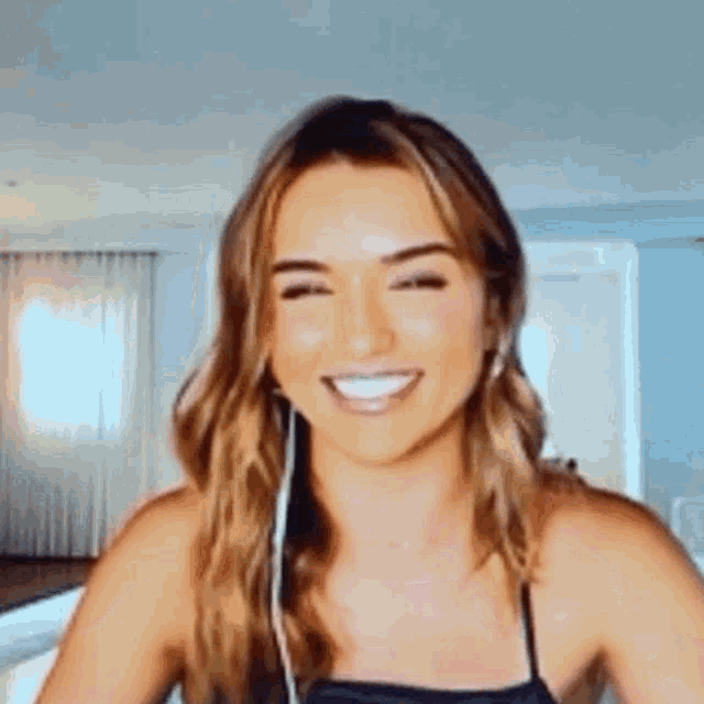 a woman is smiling while wearing headphones and making a funny face .