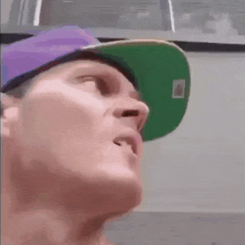 a man wearing a purple hat and a green hat looks up