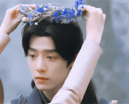 a man wearing a crown of blue flowers on his head