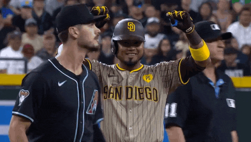 a baseball player wearing a san diego uniform is standing next to a referee .