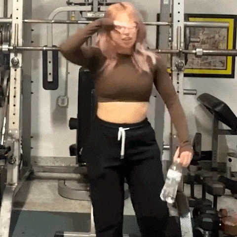 a woman is holding a bottle of water in a gym .