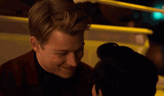 a man in a red jacket kissing another man on the cheek
