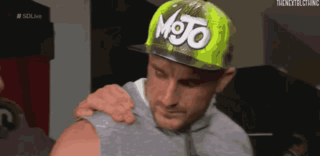 a man wearing a mojo hat holds his arm over his shoulder