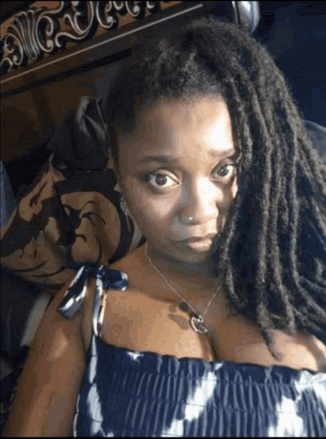 a woman with dreadlocks is wearing a blue and white polka dot dress