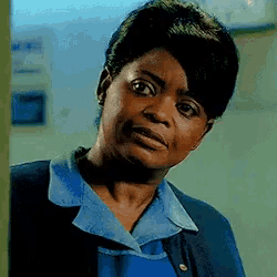a woman wearing a blue shirt and a blue jacket looks at the camera