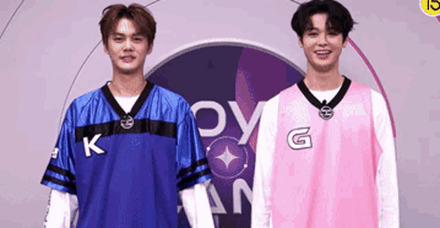 two young men are standing next to each other in front of a sign that says k and g