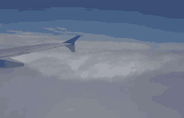 the wing of an airplane is visible in the clouds