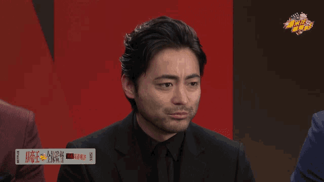 a man in a suit with chinese writing on the screen
