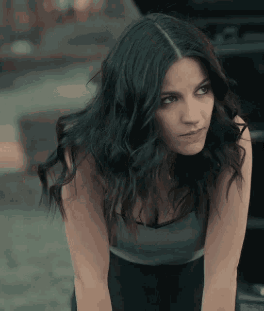 a woman with long dark hair and a gray tank top