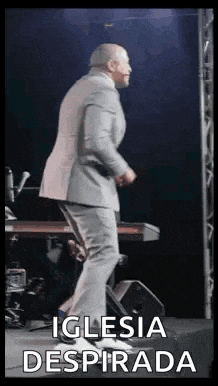 a man in a suit is dancing on a stage in front of a keyboard .