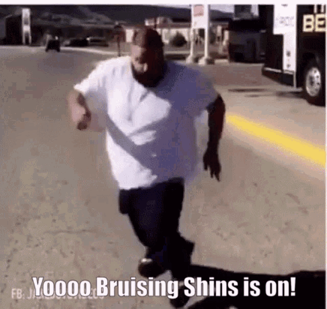 a man in a white shirt is running down the street with the words bruising shins is on .