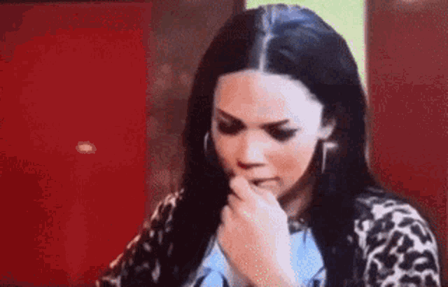 a woman is covering her mouth with her hand while looking at something .