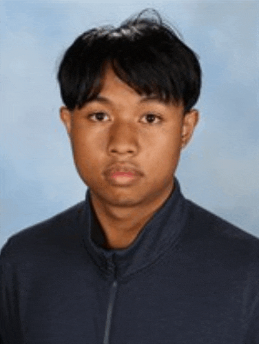 a young man is standing in front of a blue background and looking at the camera .