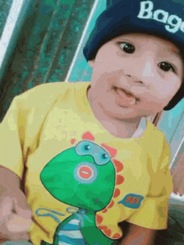 a little boy wearing a yellow shirt with a dinosaur on it