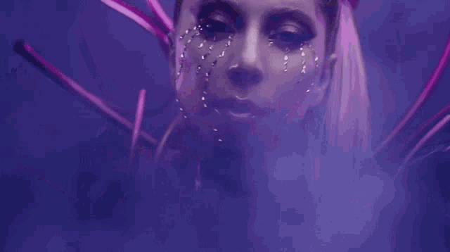 a close up of a woman 's face with purple hair and rhinestones on her face