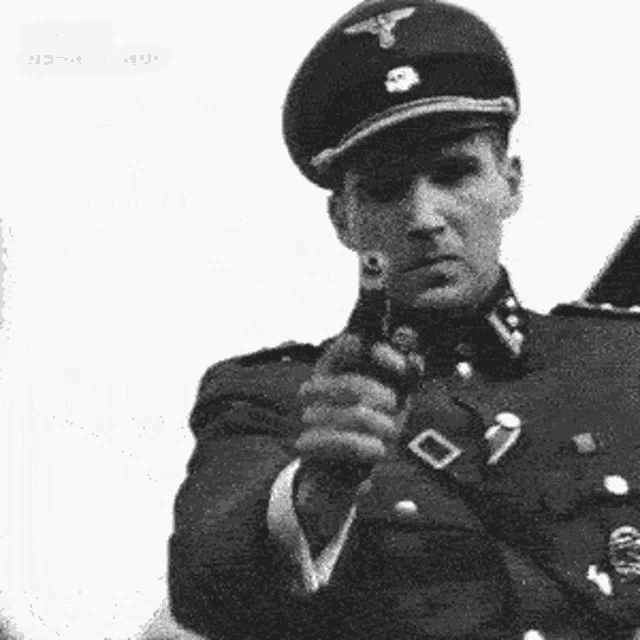a black and white photo of a man in a military uniform holding a gun .