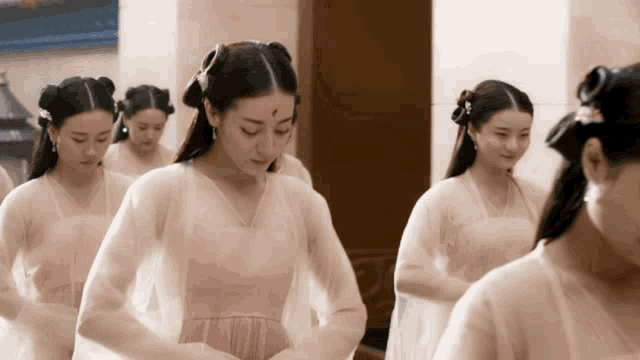 a woman with a red spot on her forehead is standing in a line with other women