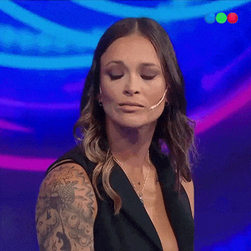 a woman with a tattoo on her arm is wearing a microphone and looking at the camera