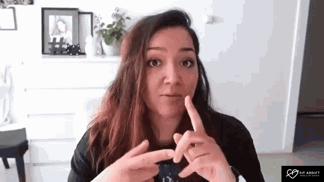 a woman is making a funny face while holding her finger to her mouth .