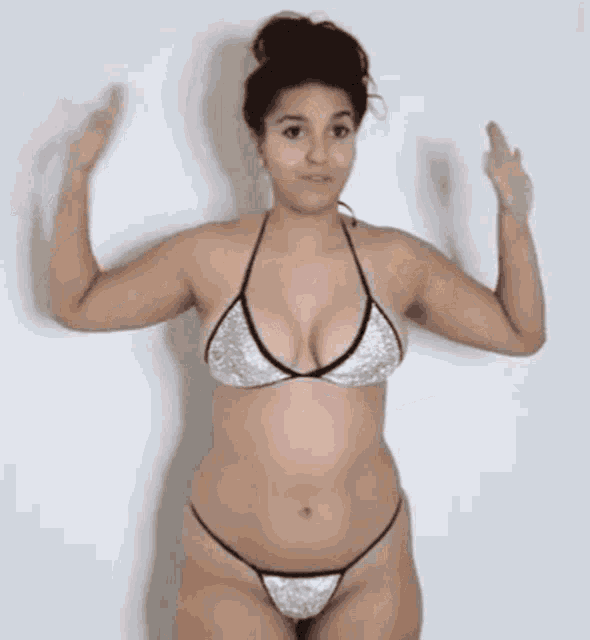 a woman in a bikini is standing in front of a wall