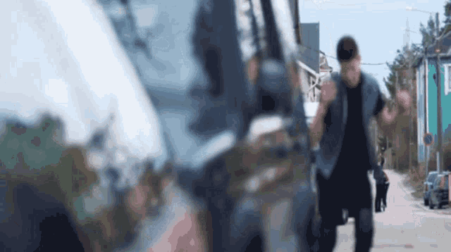 a man in a denim vest is running down the street