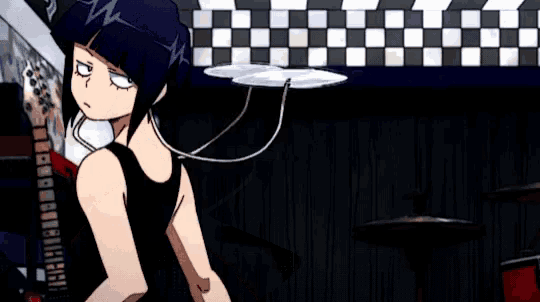 a girl in a black shirt is standing in front of a checkered wall in a dark room .